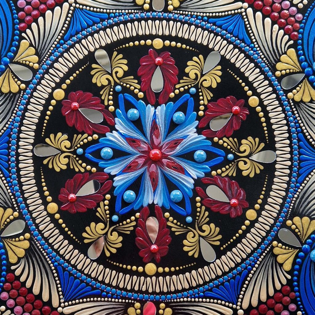 Mandala "Królewska Obfitość" autorstwa Ilony Gałysy. Centralny motyw kwiatowy w kolorach niebieskim, czerwonym i złotym z wkomponowanymi elementami lustrzanymi.