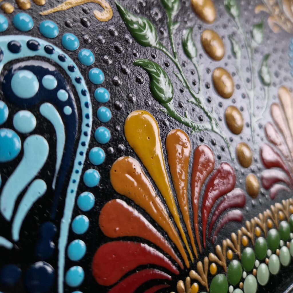 Szczegółowy widok na misterny, kolorowy ornament wykonany techniką dot paintingu na ramie lustra Ilony Gałysy.