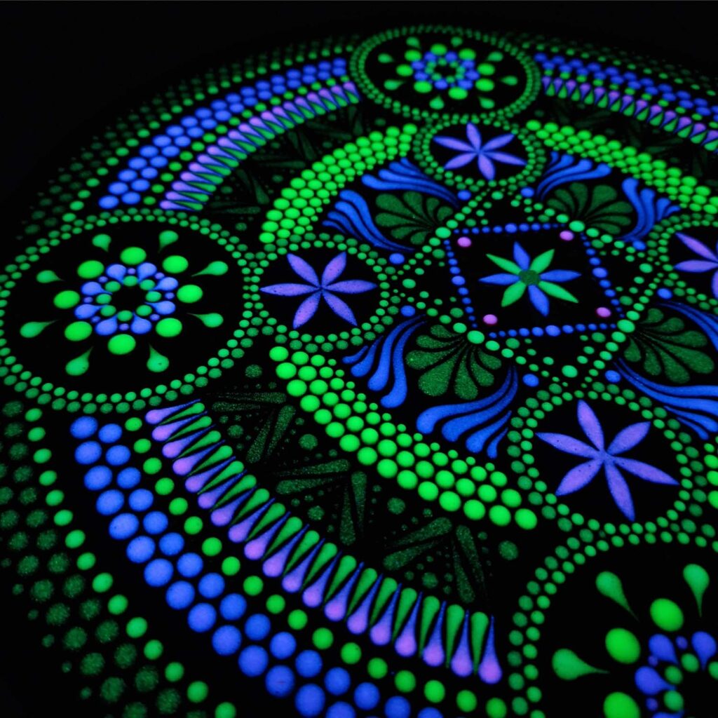 Efekt fluorescencyjny - kolorowa mandala świecąca w ciemności nasyconym światłem